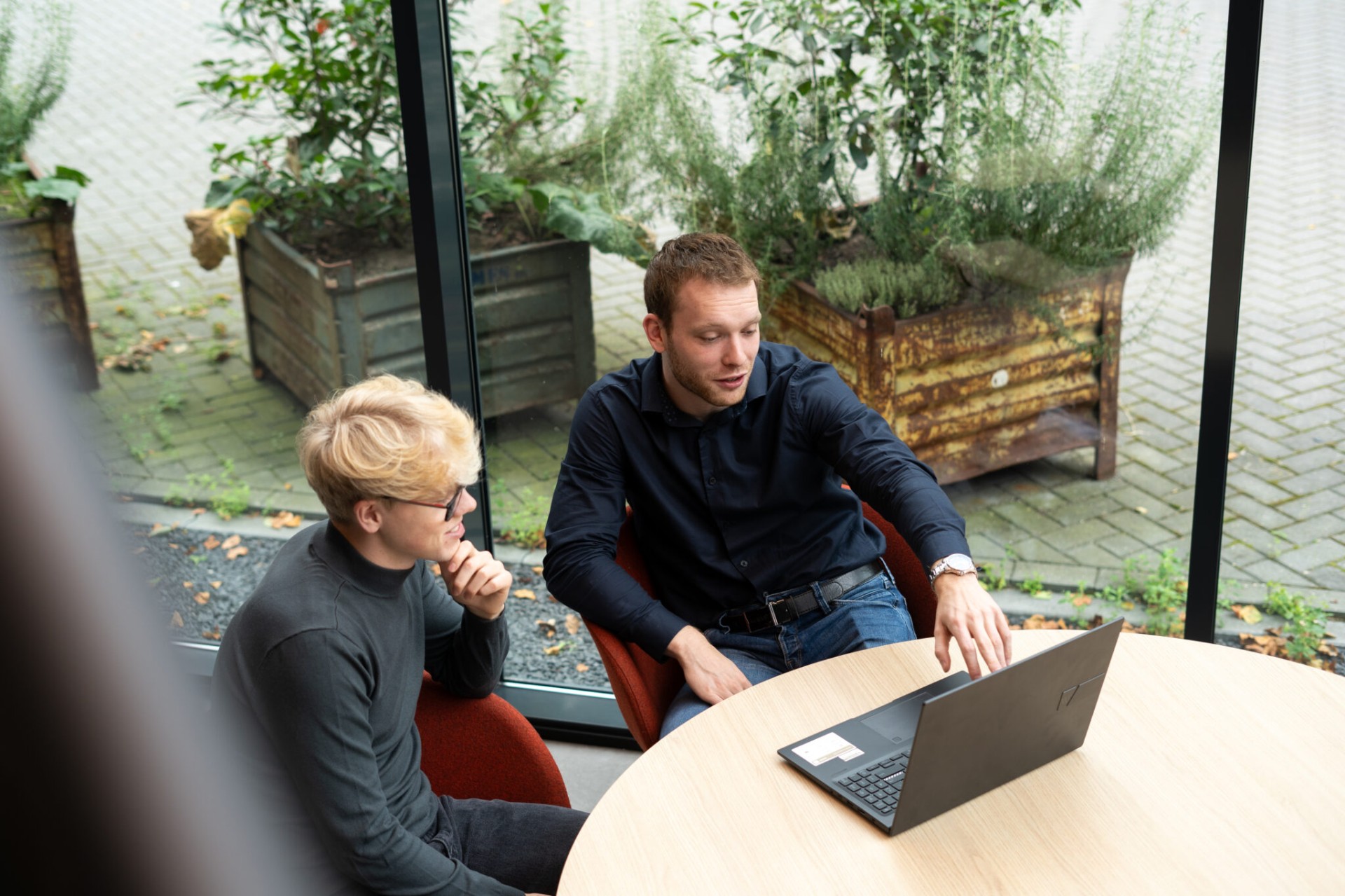 Twee collega's overleggen samen aan een tafel op kantoor